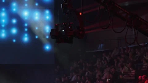 Robotic camera crane hovering over studio set with blue bokeh lights for film Stock Footage 336354144
