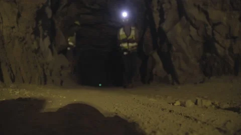 Robotic Dog Walking Through Dark Cave Corridor Alongside Cave Researcher - Stock Footage 157411416
