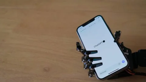 Robotic Hand Holding Iphone With AI Chat On Screen Stock Footage 247677442