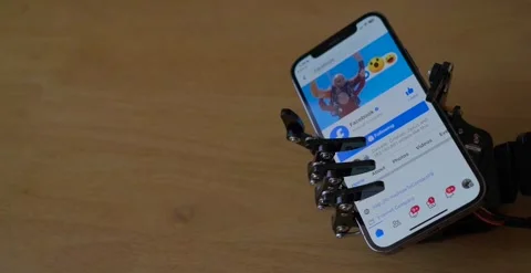 Robotic Hand Holding Phone With Facebook App on Screen Stock Footage 248090153