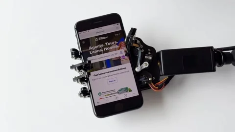 Robotic Hand Holding Smartphone While Browsing Zillow Stock Footage 277307156