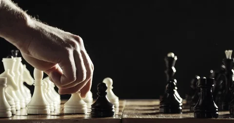 Robotic hand prosthesis is playing chess with human hand on black background. Stock Footage 106221412