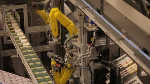 Robotic machine arms. Moving small boxes onto conveyor belt. pan C Stock Footage 102186504