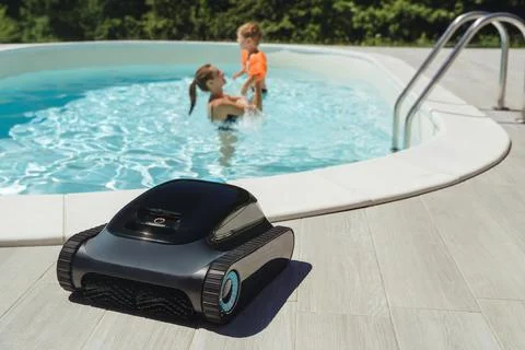 A robotic pool cleaner on the poolside with a mother and child enjoy swimming Stock Photos