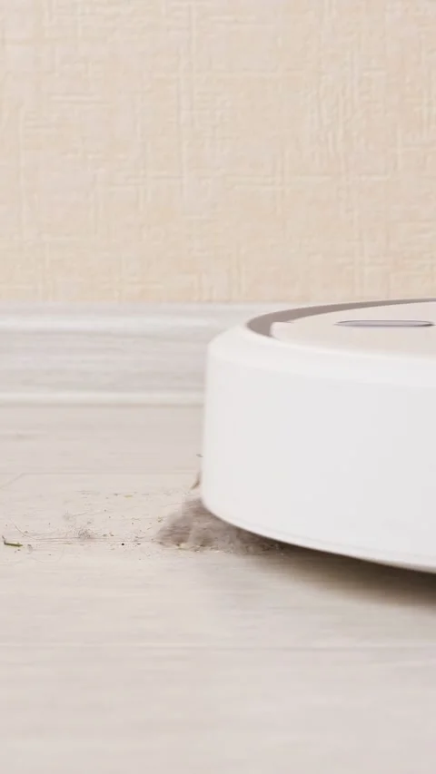Robotic vacuum cleaner cleaning dust and debris from the laminate floor, a close Stock Footage 342905162