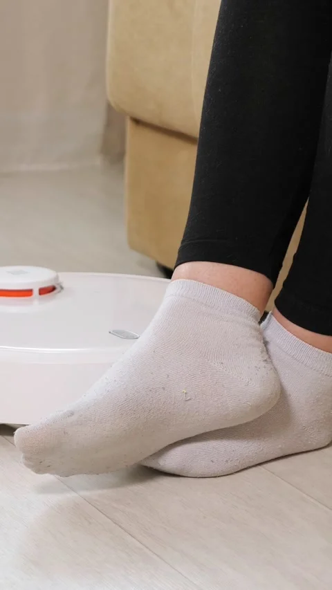 Robotic vacuum cleaner cleaning the laminate floor while a person wearing socks Video stock 341678402