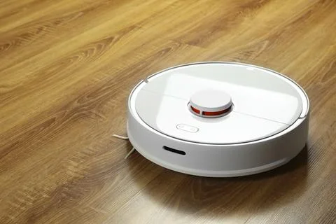Robotic vacuum cleaner on wooden floor, space for text Stock Photos