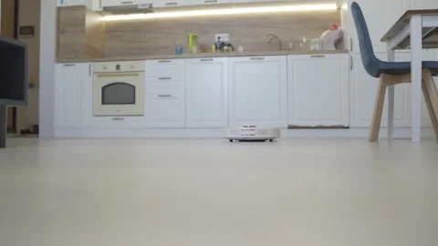 Robotic vacuum cleaner working on laminate wooden floor in the kitchen Stock Footage 219622698
