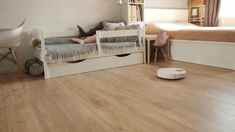 Robotic vacuum cleaner working on laminate wood floor in the living room Stock Footage 244195205