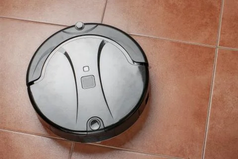 Robotic vacuum cleaner working on tile floor. smart cleaning technology Stock Photos