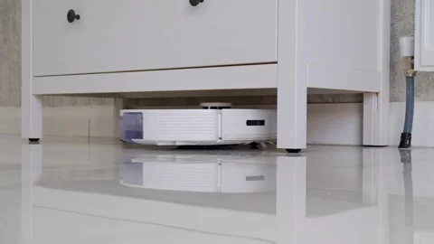 Robotic Vacuum Cleaning Under a Kitchen Cabinet on a Marble Floor Stock Footage 274880515