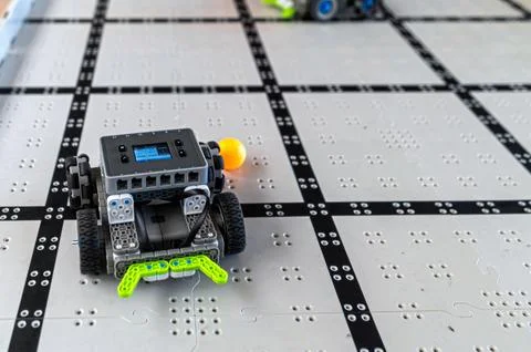 Robots competing in a technology challenge on a grid surface during a worksho Stock-Fotos