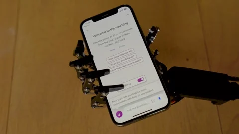 Robot's hand holding a phone with the Bing app open Stock Footage 255409752