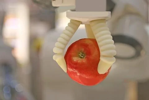 Robot's mechanical arm grabs a red apple Stock-Fotos