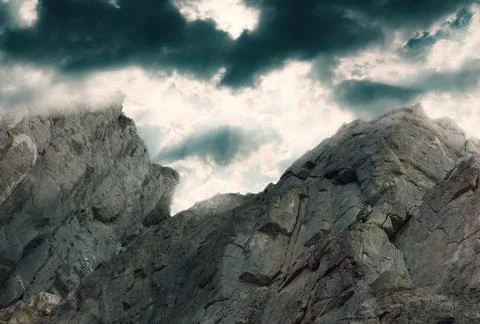 Rock against a dark dramatic sky with clouds Stock Photos