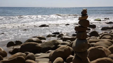 Rock balancing on the beach with waves in the background - right side of frame Stock Footage 118780599