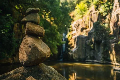Rock balancing example in front of waterfull immersed in pristine nature. Con Stock Photos