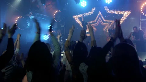 The rock band performs on stage with a light show. The crowd is dancing. Stock Footage 194546753