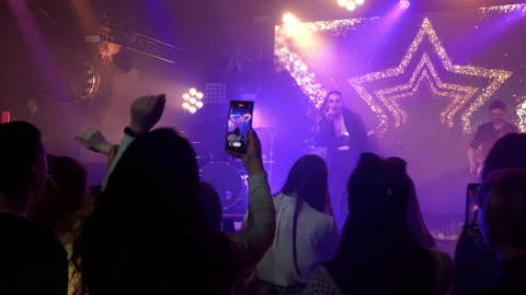 The rock band performs on stage with a light show. The crowd is dancing. Stock Footage 194547201