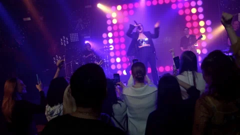 The rock band performs on stage with a light show. The crowd is dancing. Stock Footage 194548793