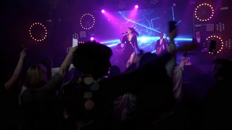 The rock band performs on stage with a light show. The crowd is dancing. Stock Footage 194549432