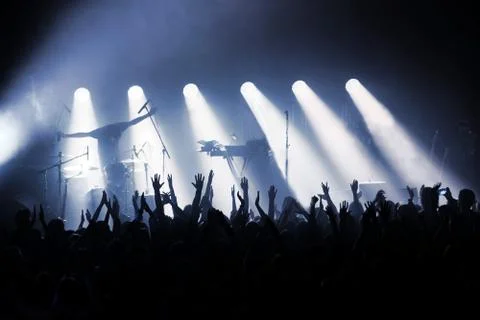 Rock band on stage in rays of spotlights in front of crowd Stock Photos
