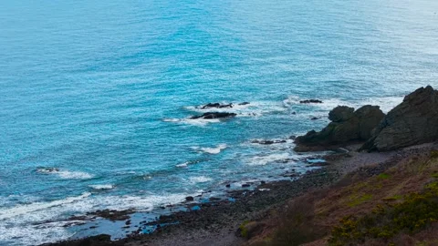 Rock beach with waves rolling over large coastal boulders. Stony shoreline Stock Footage 306537259