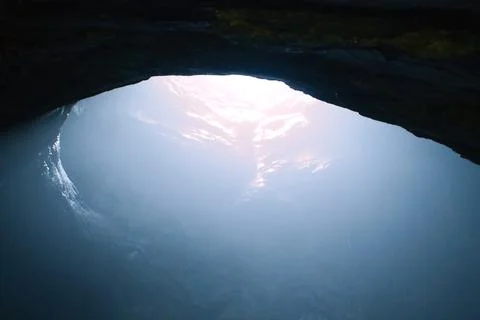 Rock cave with hole through which light shines. Underworlds in Sweden. Mystic Stock Photos