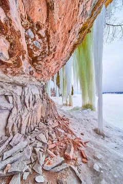 Rock cliffs with large icicles hanging by frozen lake Stock-Fotos