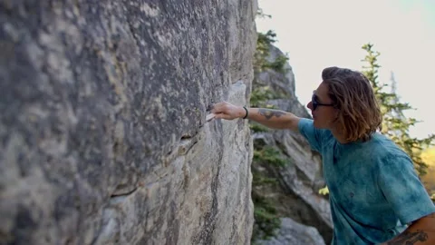 Rock climber brushing off rock, boulder 库存影片 220306125
