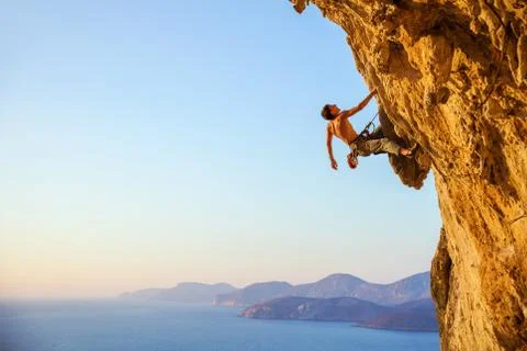 Rock climber on cliff at sunset Stock Photos
