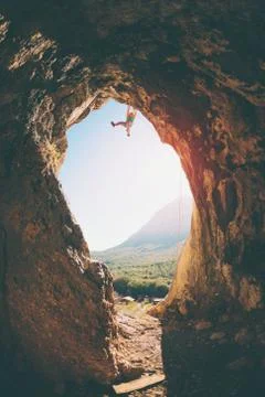 Rock climber climbs into the cave. Rock in the form of an arch. The woman tra Stock Photos