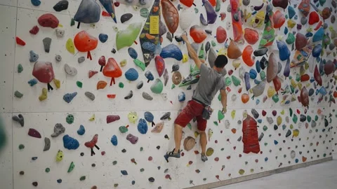A rock climber guy trains on a special tena in the gym Stock Footage 158481475