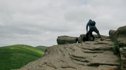 Rock climber helping friend pull up on the rock. Hiking in mountains 4K. Stock Footage 234571132