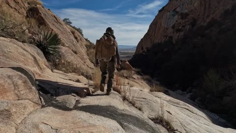 A rock climber hiking through a rugged desert canyon Video stock 329768166