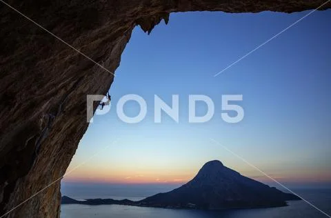 Rock climber on overhanging cliff at sunset Stock Photos