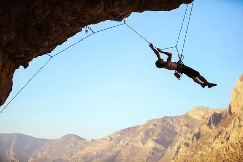 Rock climber pulling himself up using rope Stock Photos