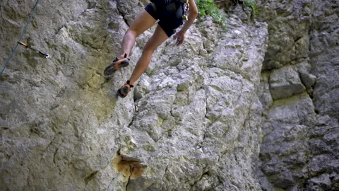 Rock climber testing climbing sockets and footholds during rock face climb Video stock 131838712