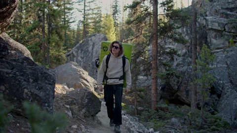 Rock climber walks through boulder field with crash pad on back 库存影片 220305905