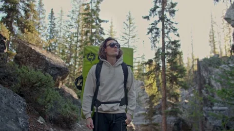 Rock climber walks through boulder field with crash pad on back 库存影片 220305908