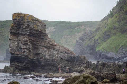 Rock climbing on dramatic seaside cliffs with green hills in background Stock Photos