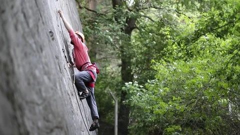 Rock climbing man on a vertical stone wall holding with one hand and going up. 스톡 동영상 73041194