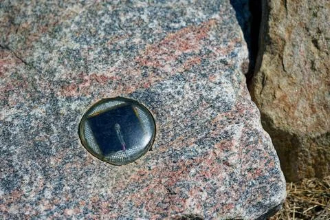 Rock embedded reflective marker with arrowed Solar sensor panel. Stock Photos