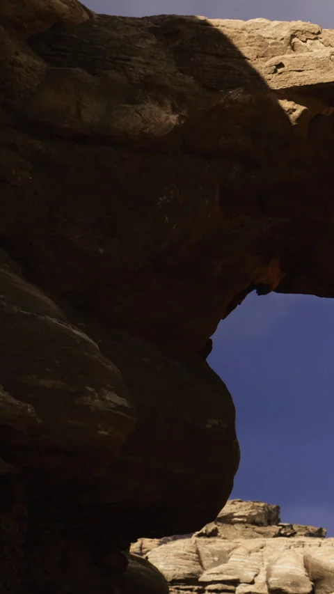 Rock formation with an arch under a blue sky near a desert landscape Stock Footage 334262174