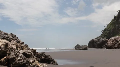 Rock formation on a beach with two people in the distance, Indonesia Stock Footage 217787735