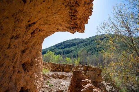 Rock formation frames beautiful view of lush green hills under clear blue s.. Stock Photos