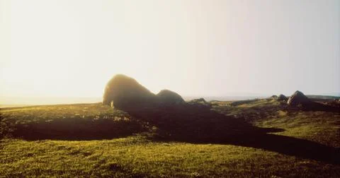 Rock formations create interesting shadows at sunrise over hillside Ilustração Stock
