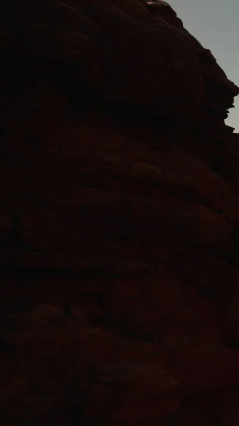 Rock formations at dusk in a desert landscape near a mountain range Stock Footage 342167496