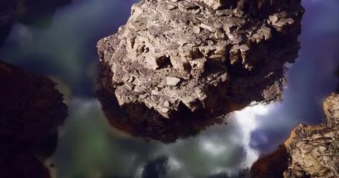 Rock formations reflect in tranquil waters under bright daylight Ilustração Stock