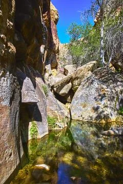 Rock Formations Reflected in Clear Water with Lush Greenery and Sunlit Cany.. Фото
